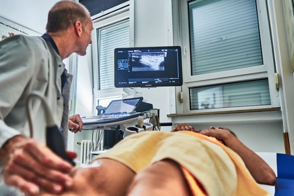 Arzt führt eine Sonographie am rechten Bein durch Arzt führt eine Sonographie am rechten Bein durch