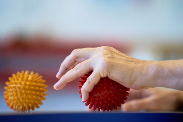 Eine Hand greift nach einem roten Igelball Eine Hand greift nach einem roten Igelball