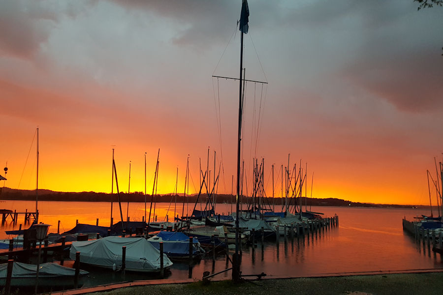 Boote liegen am Steg am See im Sonnenuntergang Boote liegen am Steg am See im Sonnenuntergang